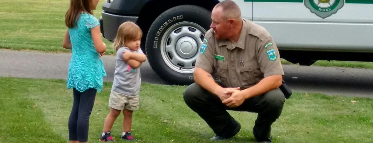 Park ranger talking with children in front of truck 