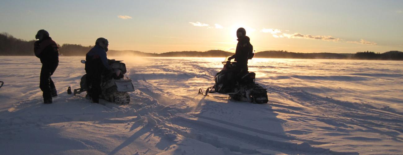 3 snowmobiles at sunset