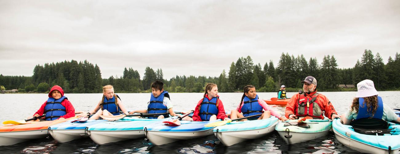 young participants in a kayak safety course on the water, all wearing lifejackets