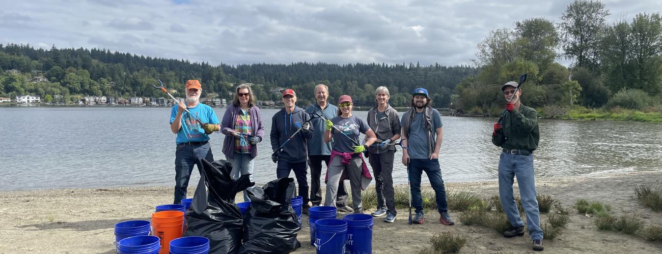 Volunteers posing with trash buckets and grabbers in front of Lake Sammamish.