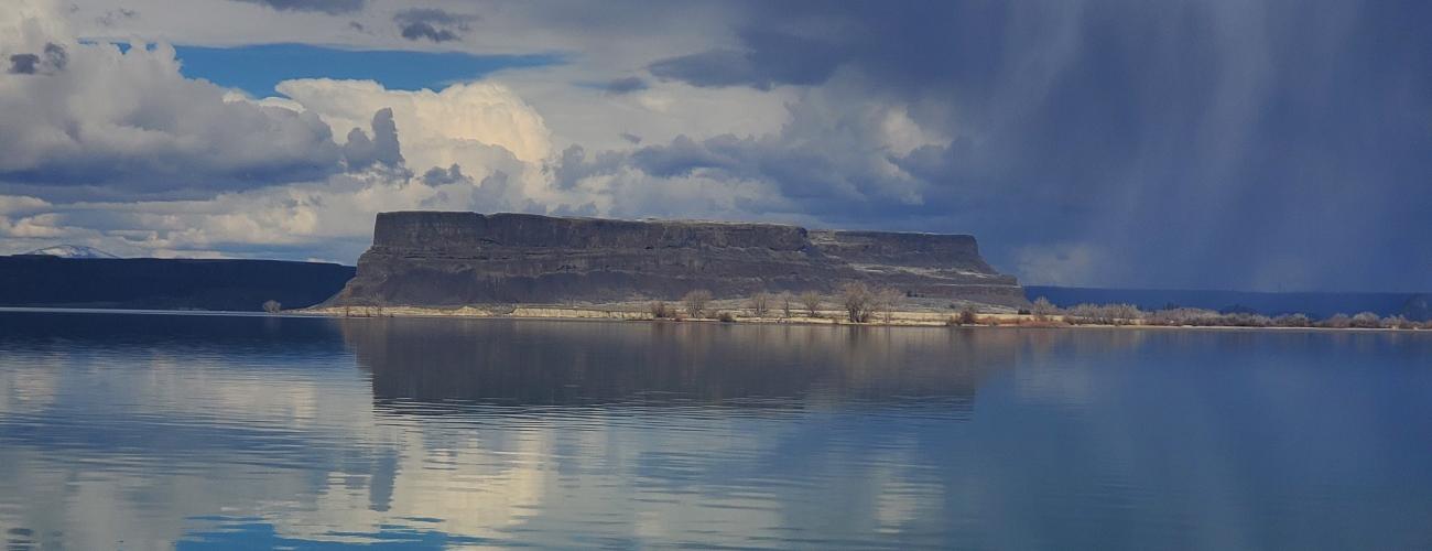 large rocky cliffs rising above calm lake water