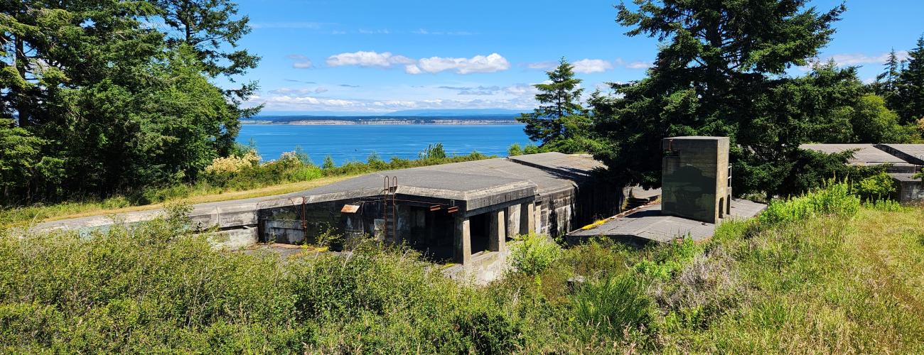 A beautiful view of the forts, mountains and water at Fort Worden State Park on a sunny, blue-sky day