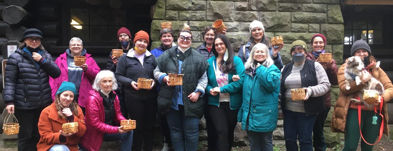 Melissa Peterson cedar bark basket class students holding their baskets in front of a kitchen shelter