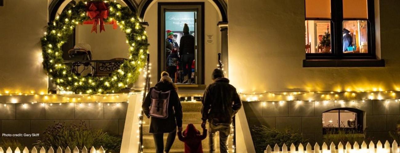 Family with young child enters the lighthouse decorated for the holidays