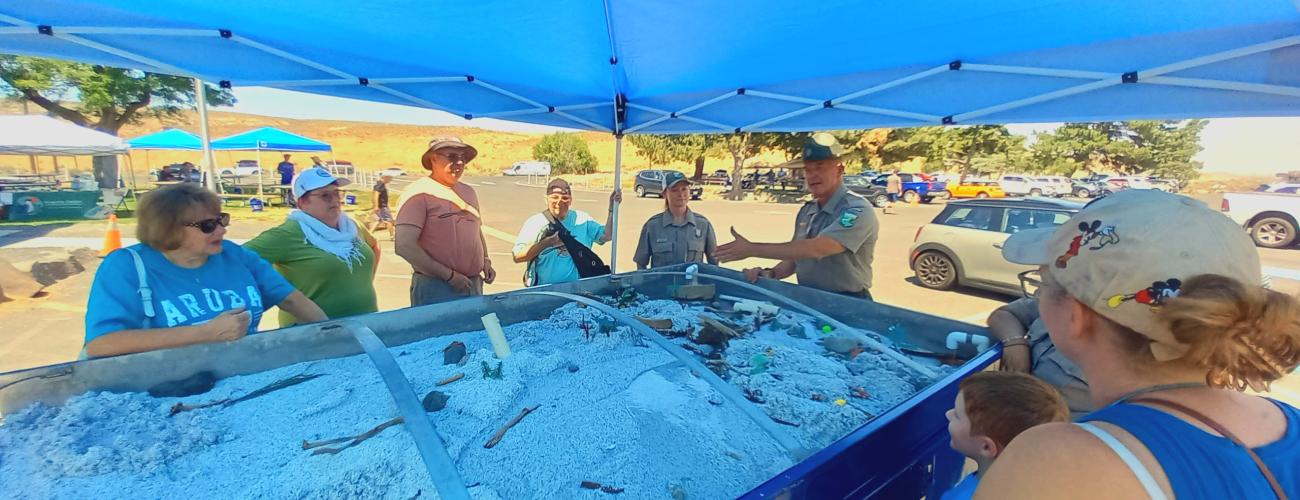 People standing around a display of the Ice Age floods in Coulee City WA while Ranger David McWalter explains what happened