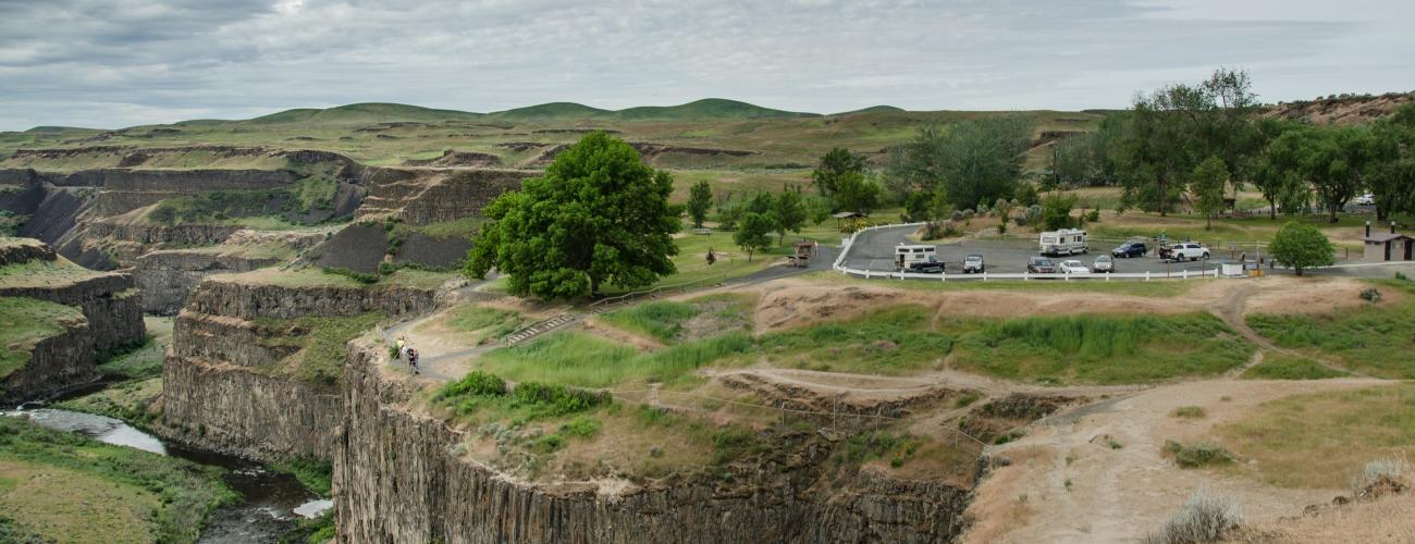 A parking lot with a short trail to an overlook at the edge of a canyon. A river is flowing below.