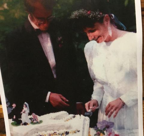 A bride and groom cut a cake with edible flowers.