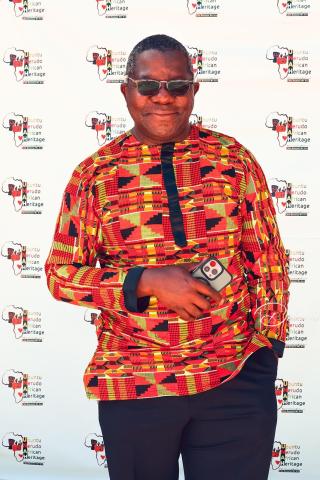 Man dressed in traditional African clothing in front of a backdrop.