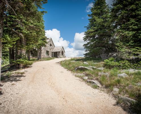 The stone Vista House is shown at the end of a gravel trail lined with trees.