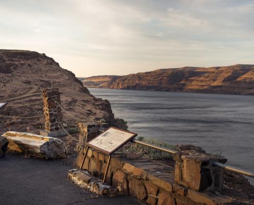 Interpretive displays overlooking Wanapum Lake. Sunset lit cliffs acoss the lake with cloudy blue sky.