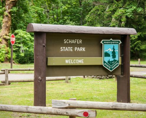 Schafer Welcome sign with trees visible in the background and a fence surrounding the sign.