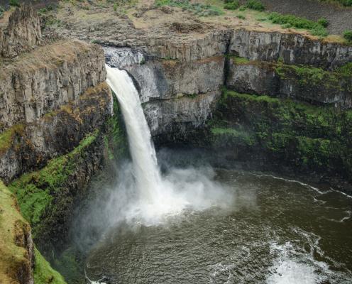 A large waterfall pours over a cliff.