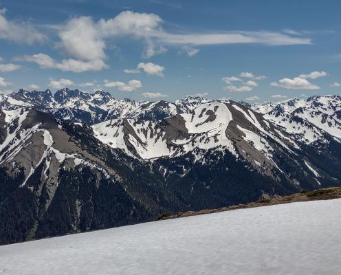 Snowy mountain range sits beyond field of snow