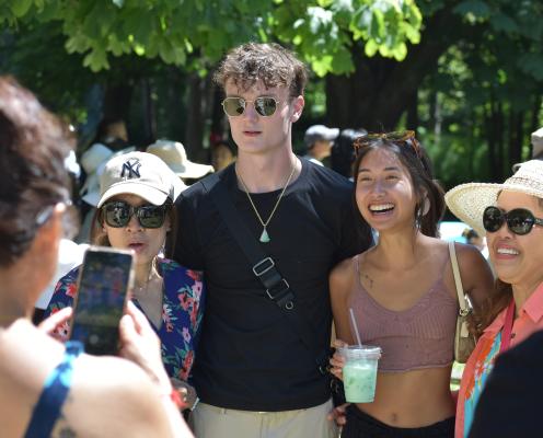 A young man and woman stand together. One is white, one is Asian. Family surrounds them.