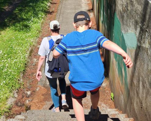 A women in a white shirt and jeans and boy in a blue shirt and red shorts walking down some stairs at one of the forts at Fort Worden State Park.
