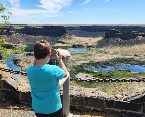 Kid looking to the binoculars at the Dry Falls Visitor Center