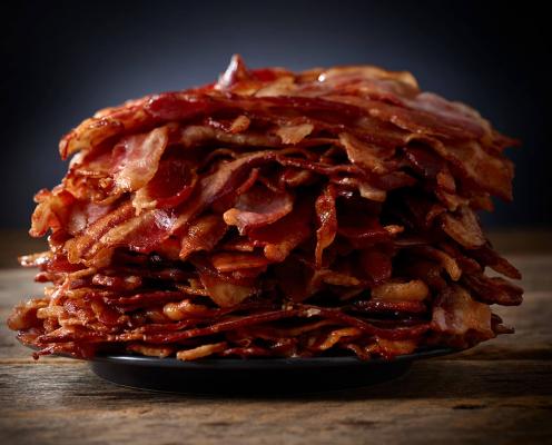 A giant pile of bacon on a sandwich.