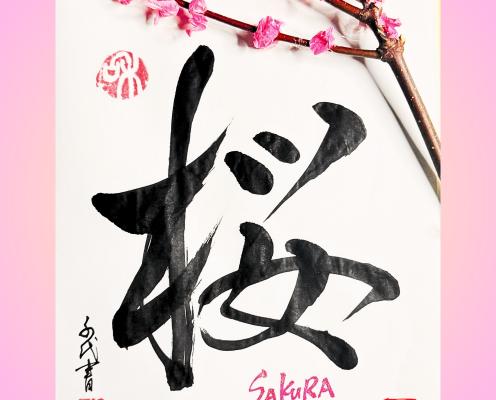 A Japanese character (kanji) that means sakura cherry blossom, a branch of cherry blossom on top and a Japanese signature and some red stamps on white paper.