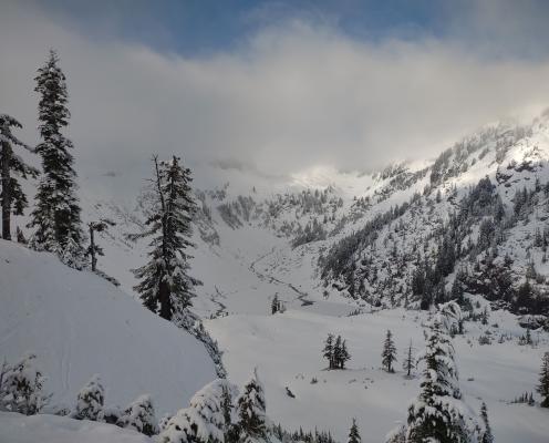 Mt Baker NRA view of a snowy, semi forested basin with a river running through it.
