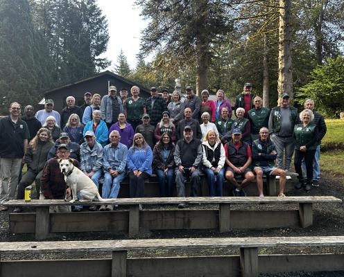 A group of people sit for a photo in front of trees.