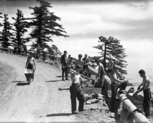 historic black and white photo of workers building guardrail on cliffside road