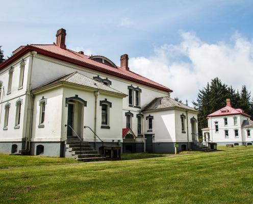 An exterior view of two lighthouse keepers residences with white stucco and red roofs on a lawn