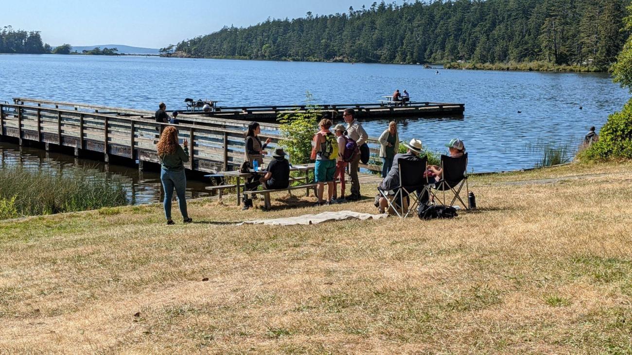 Nina Vichayapai speaks with park visitors on a sunny day near a picnic table at Cranberry Lake