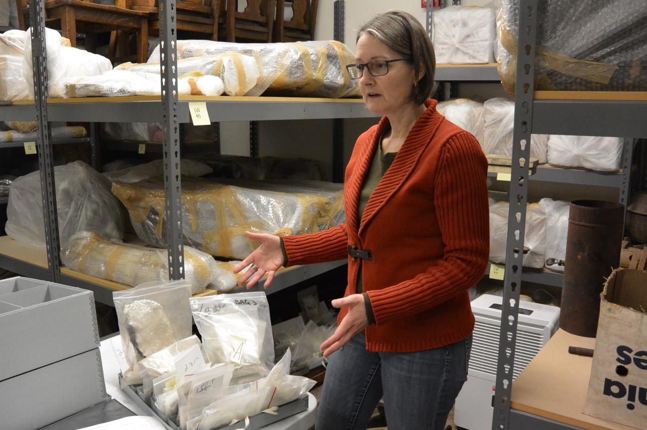 Woman stands in a room filled with boxes of artifacts