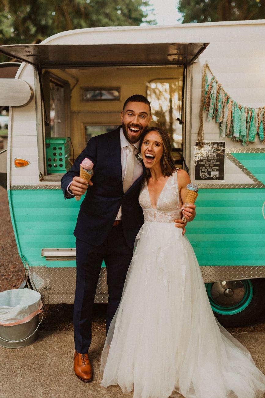 A bride and groom hold ice cream cones in front of an ice creat truck