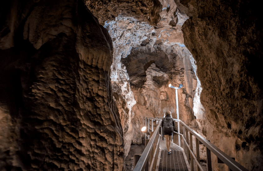 A person walks down an elevated path through a cave