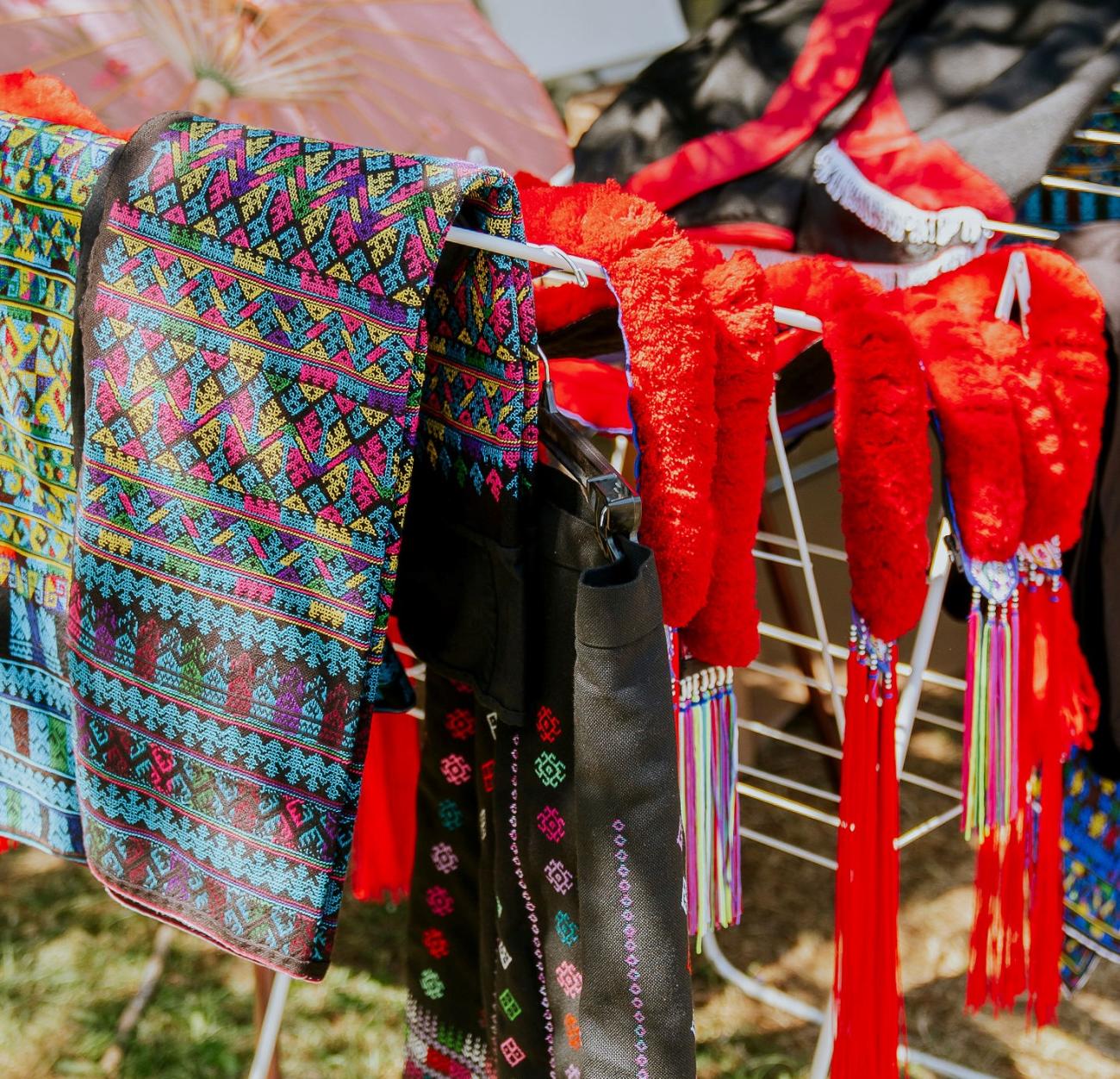 Colorful textiles are draped over hangers