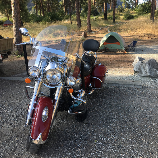 A motorcycle is parked in front of a campsite with a tent