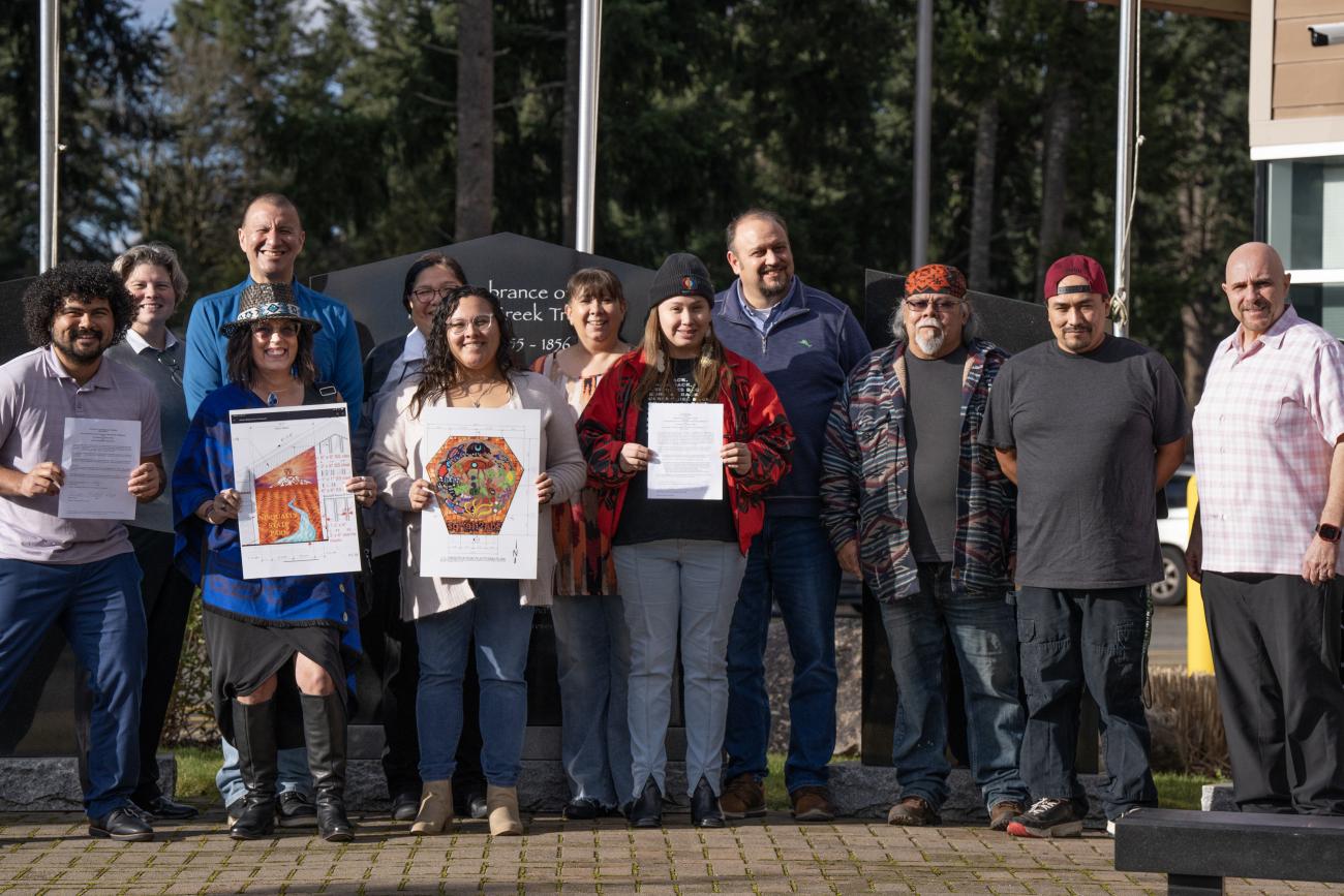 Leadership from the Nisqually Tribe and Parks show off signed documents and artwork