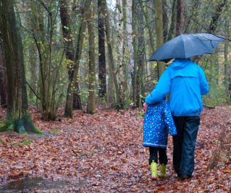 Adult and kid walking along path in the rain