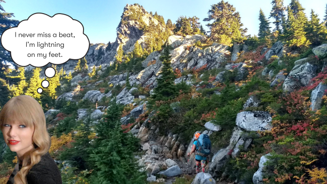 A woman hikes up a mountain trail with white granite and fall colors. In a corner, a cutout of Taylor Swift has a thought bubble saying, "I never miss a beat, I'm lightning on my feet."
