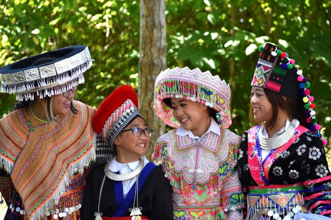 A group of women from Laos pose in traditional beaded and embroidered dress.