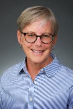 Headshot of Commissioner Laurie Connelly, Vice Chair wearing a blue and white striped shirt and black glasses.