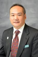 Headshot of Commissioner Michael Latimer wearing a black suit jacket, white shirt and a burgandy printed tie.