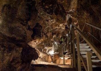 A metal walkway sits above the formations inside of the cave.