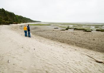 expansive beach with two people looking out at the marsh 