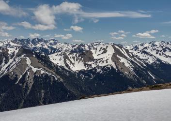 Snowy mountain range sits beyond field of snow