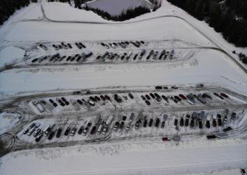 Overhead view of two long plowed parking areas covered by light snow surrouded by snow-covered ground. One lot fits 40 trucks, the other fits about 50 trucks.
