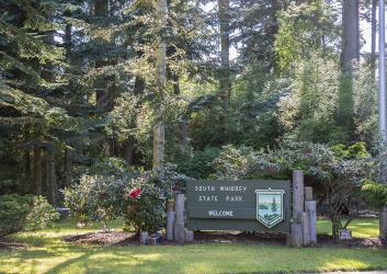 Welcome sign with trees and flowers
