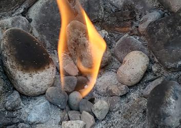 dancing flame rising from pebbles on the ground