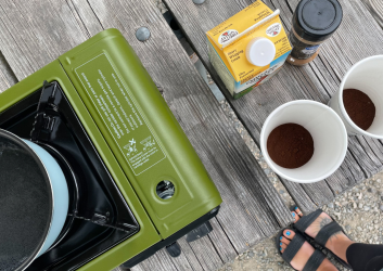 person boiling water for coffee on a single burner camp stove