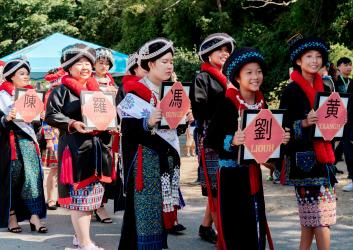 A group of Iu Mien women march in a community parade in traditional dress.