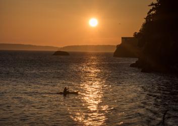 kayaker paddling near shore at sunset