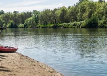 sand beach beside river with kayak resting on beach