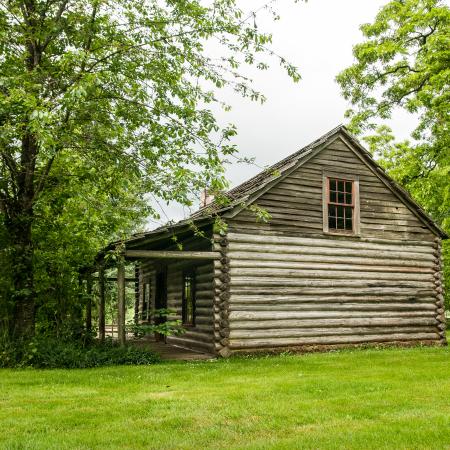 side view of log cabin with porch large grassy field