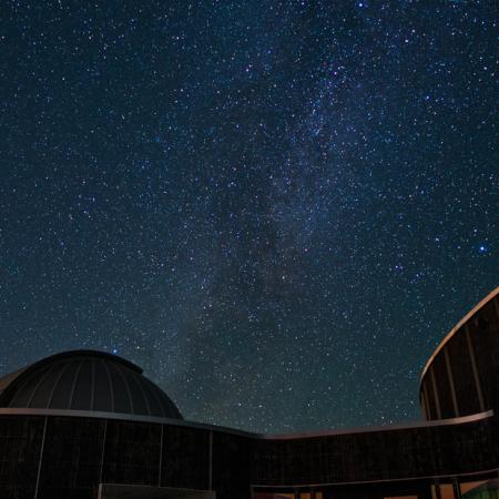 Starry night sky over observatory building.